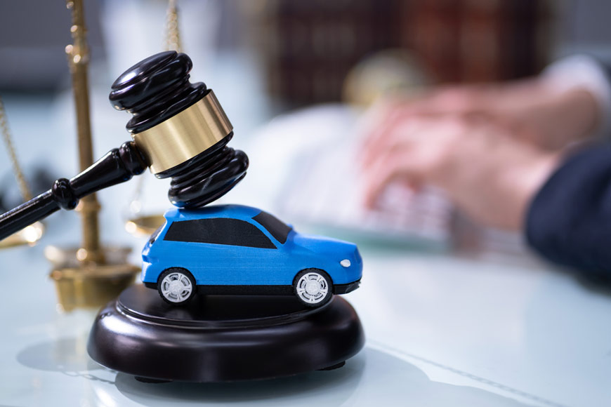 Figurka samochodu pod młotkiem sędziowskim nawiązująca do regresu ubezpieczeniowego po wypadku motoryzacyjnym – actavera.eu